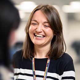 A woman who is smiling and greeting a student.