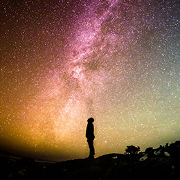 Silhouette of the person looking at a star-filled sky.