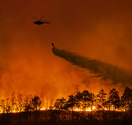 Helicopter drops water on to a forest fire.